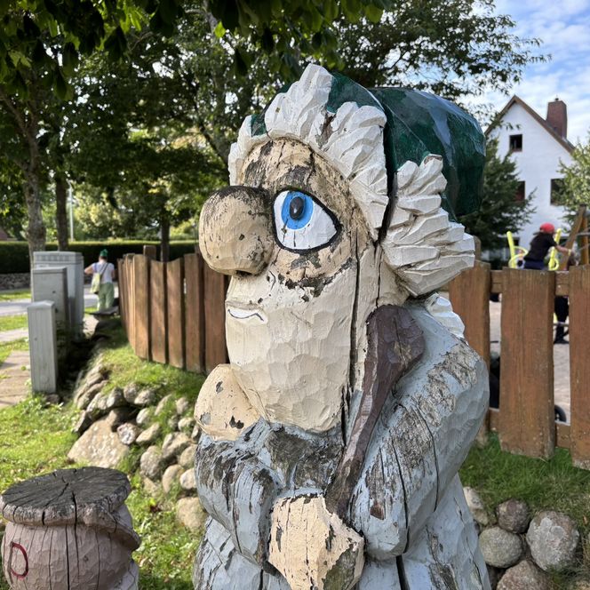 Holzfigur Puk mit grünem Hut und Löffel, seitlich fotografiert. 