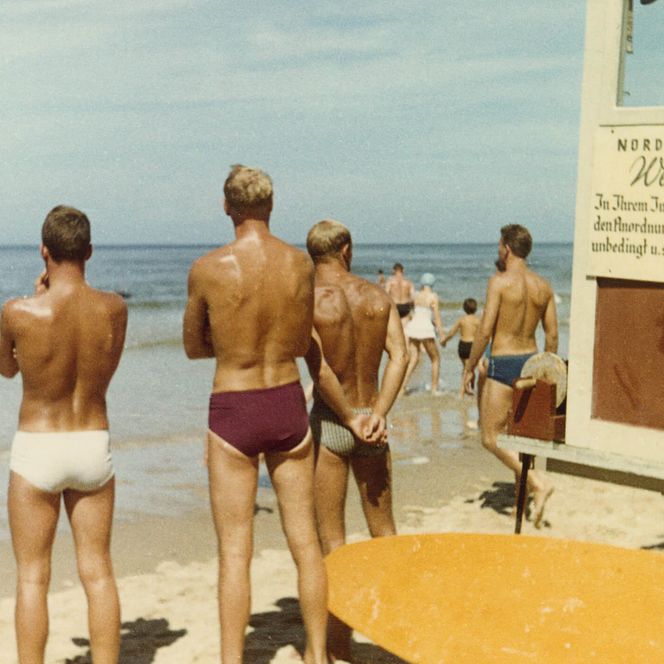 Männer in Badehosen schauen auf das Meer in Westerland
