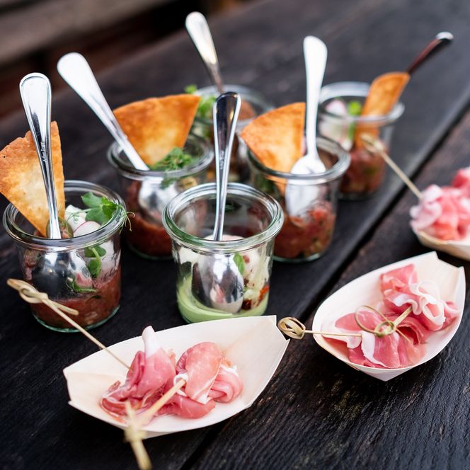 Appetithäppchen in Gläsern und Holzschalen mit Löffeln 