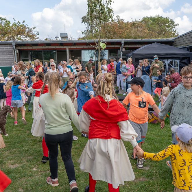 Kinder tanzen beim M.T. Buchholz Hoffest auf einer Wiese im Kreis.