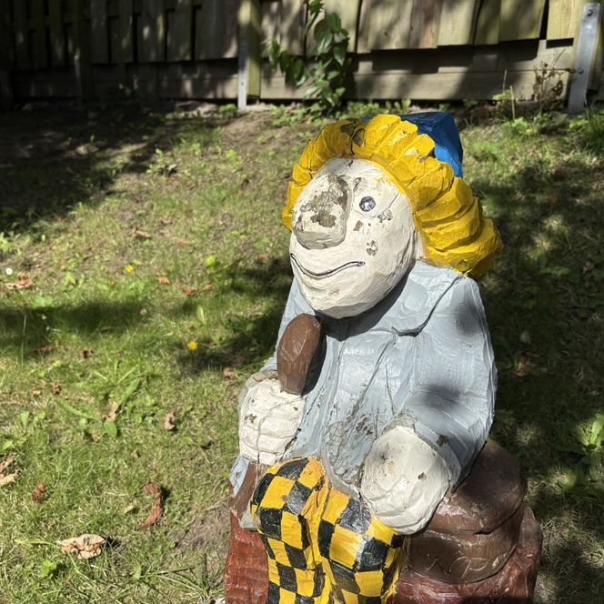 Puken-Holzfigur mit Löffel und bunter Mütze auf Baumstumpf