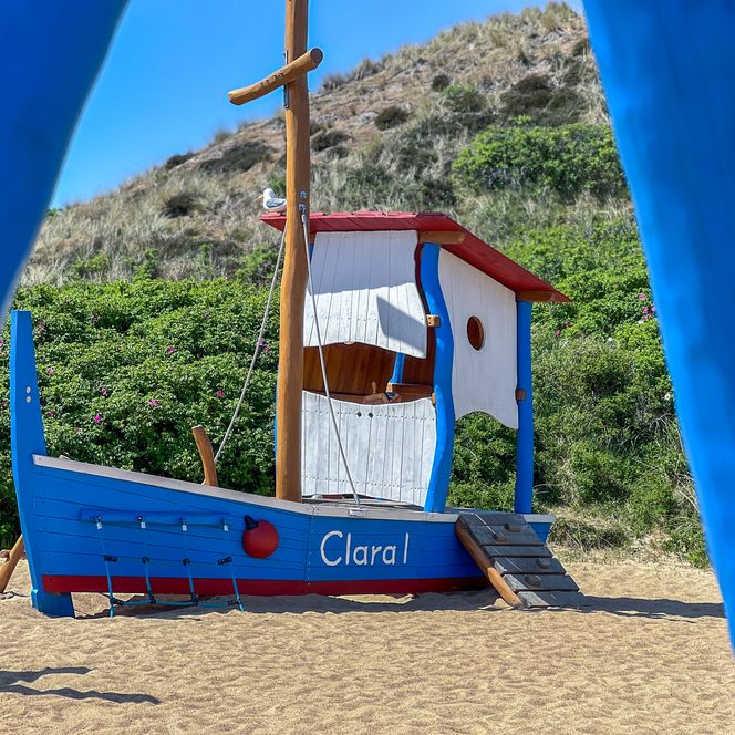 Spielschiff in blau und weiß auf Sand