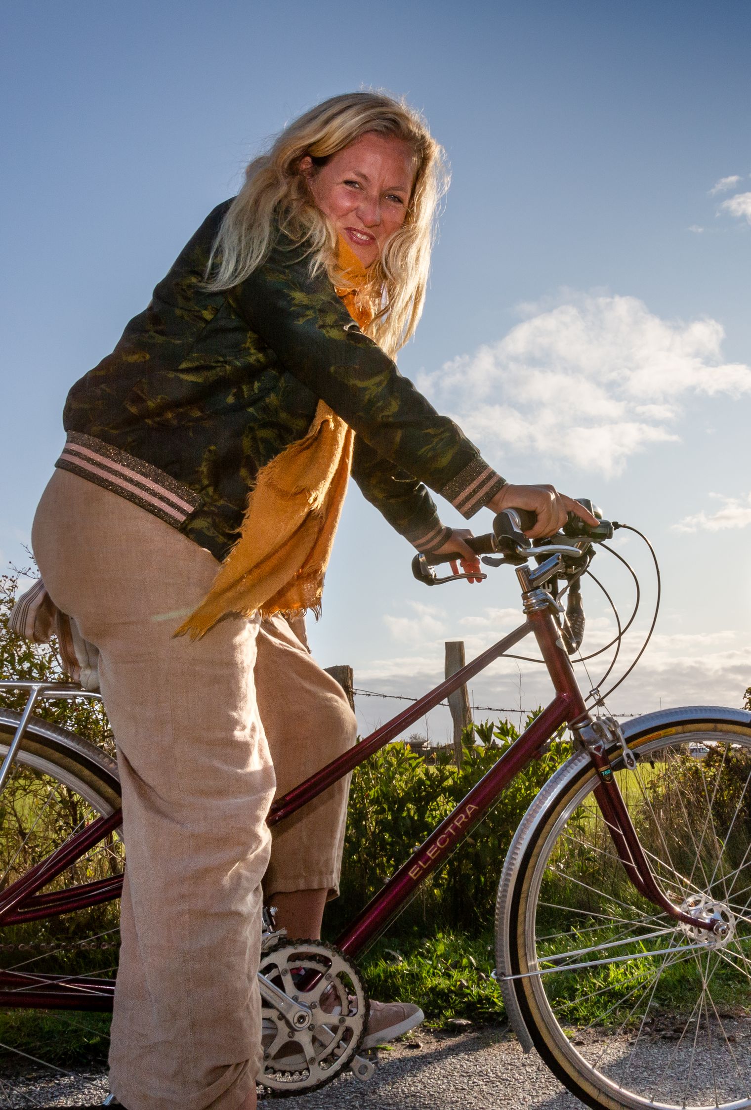 Imke Wein, Natürlich Sylt-Kolumnistin, auf rotem Fahrrad bei Sonnenschein draußen.