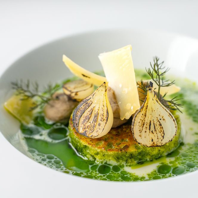 Fein angerichtetes Gericht mit gebratenen Zwiebeln, Käse und Kräutersauce beim Private Dining auf Sylt.