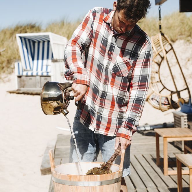 Ein Mann macht einen Aufguss vor der Strandsauna List.