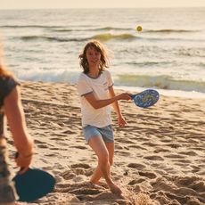 Jugendliche spielen Beachball am Strand bei Sonnenuntergang.