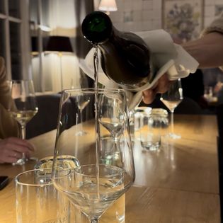 Nahaufnahme eines Weißweinglases, in das gerade eingefüllt wird