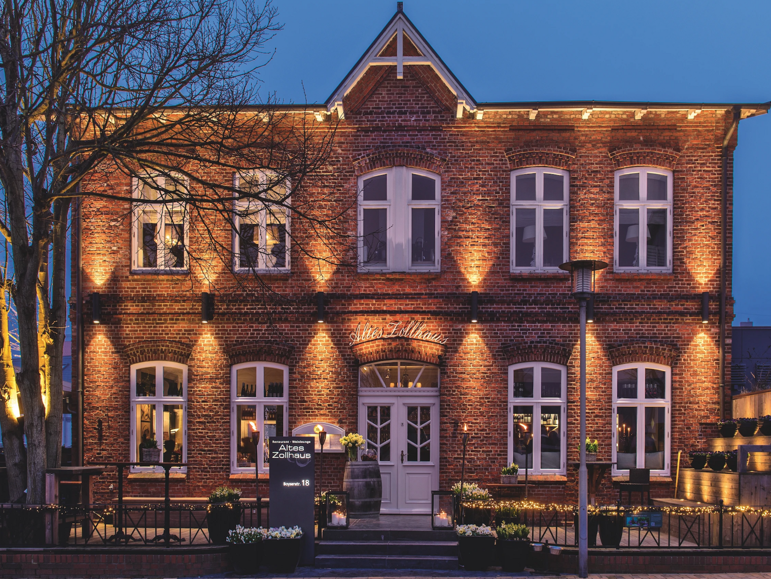 Backsteingebäude „Altes Zollhaus“ bei Abendbeleuchtung