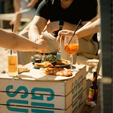 Menschen essen gemeinsam draußen an improvisiertem Tisch.