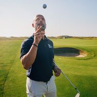 Golfer bereitet sich auf Schlag mit schwebendem Ball vor.