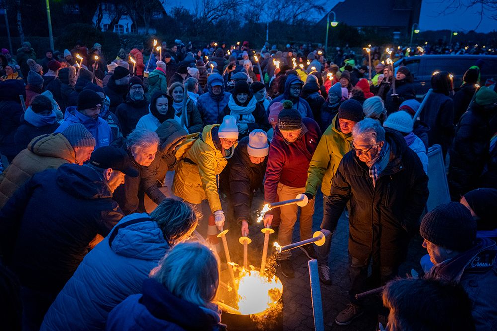Menschen entzünden Fackeln an Feuertonne
