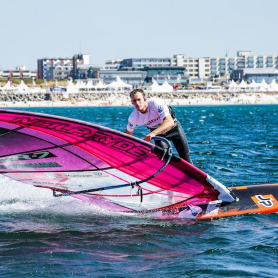 Windsurfer mit pinkem Segel vor Strand und Promenade auf Sylt
