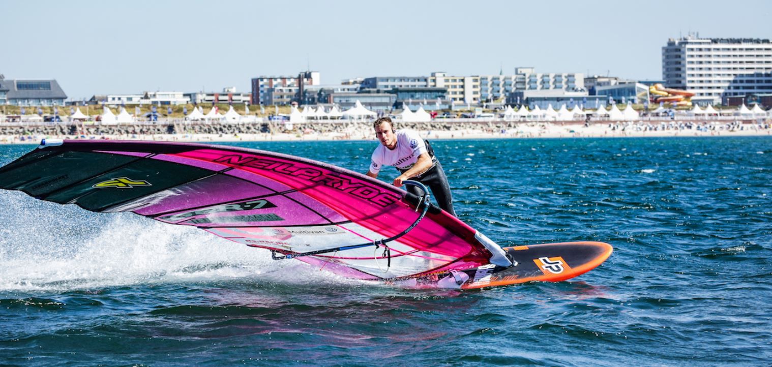 Windsurfer mit pinkem Segel vor Strand und Promenade auf Sylt