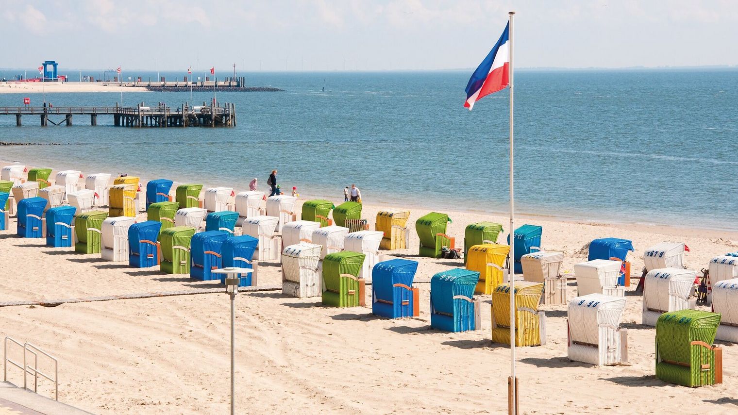 Bunte Strandkörbe am Strand mit Seebrücke
