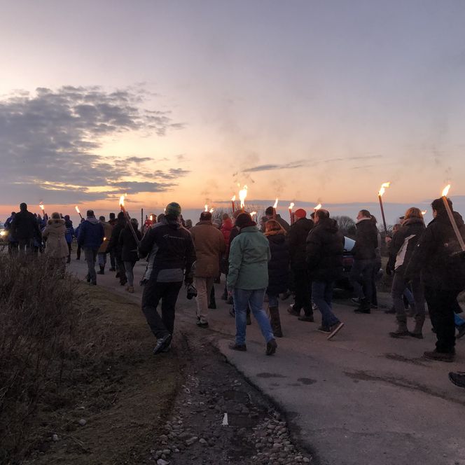 Menschen mit Fackeln laufen einen Feldweg entlang