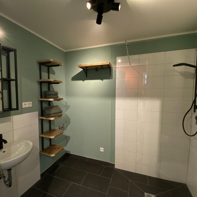 Modernes Bad mit bodengleicher Dusche, klaren Linien und praktischer Ausstattung – funktional und stilvoll zugleich.