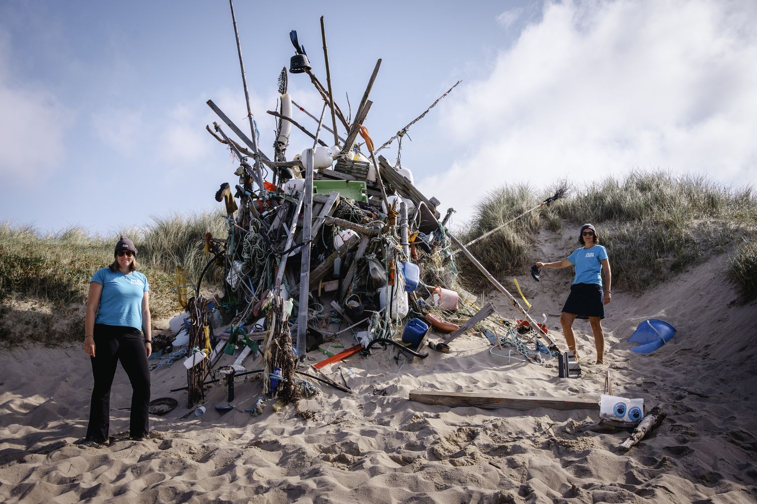 Zwei Frauen stehen vor Skulptur aus angespültem Plastikmüll in den Dünen.