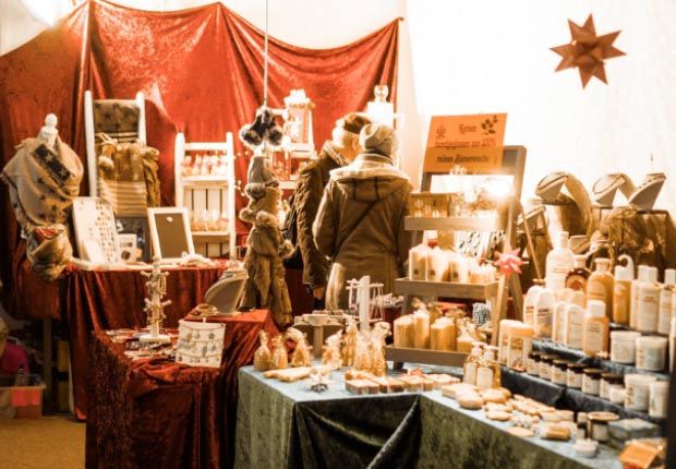 Scheunenmarkt bei der Sylter Landschlachterei in Keitum Festlich dekorierter Marktstand mit handgemachten Produkten wie Kerzen und Seifen, umgeben von weihnachtlicher Atmosphäre.