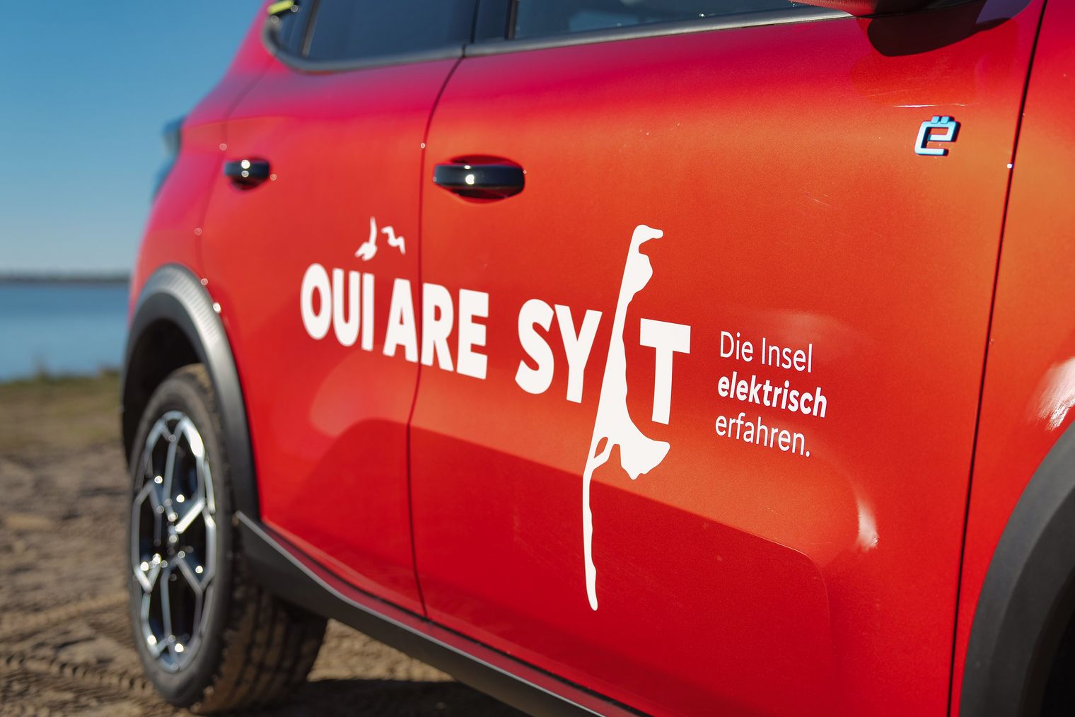 Rotes E-Auto mit Aufschrift „OUI ARE SYLT“