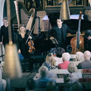 Musiker verbeugen sich nach Kammerkonzert in festlich beleuchteter Kirche auf Sylt.