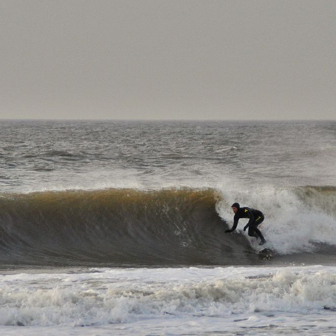 Surfer in den Winterwellen der Nordsee Surfer in Neoprenanzug reitet Welle auf der Nordsee.