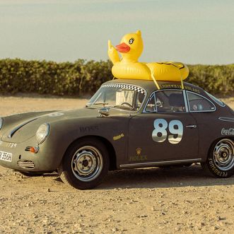 Alter Sportwagen mit großer gelber Badeente auf dem Dach.