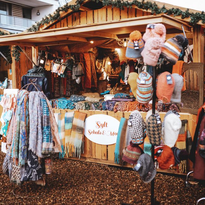 Holzstand mit bunten Schals, Mützen und Accessoires auf dem Sylter Wintermarkt.
