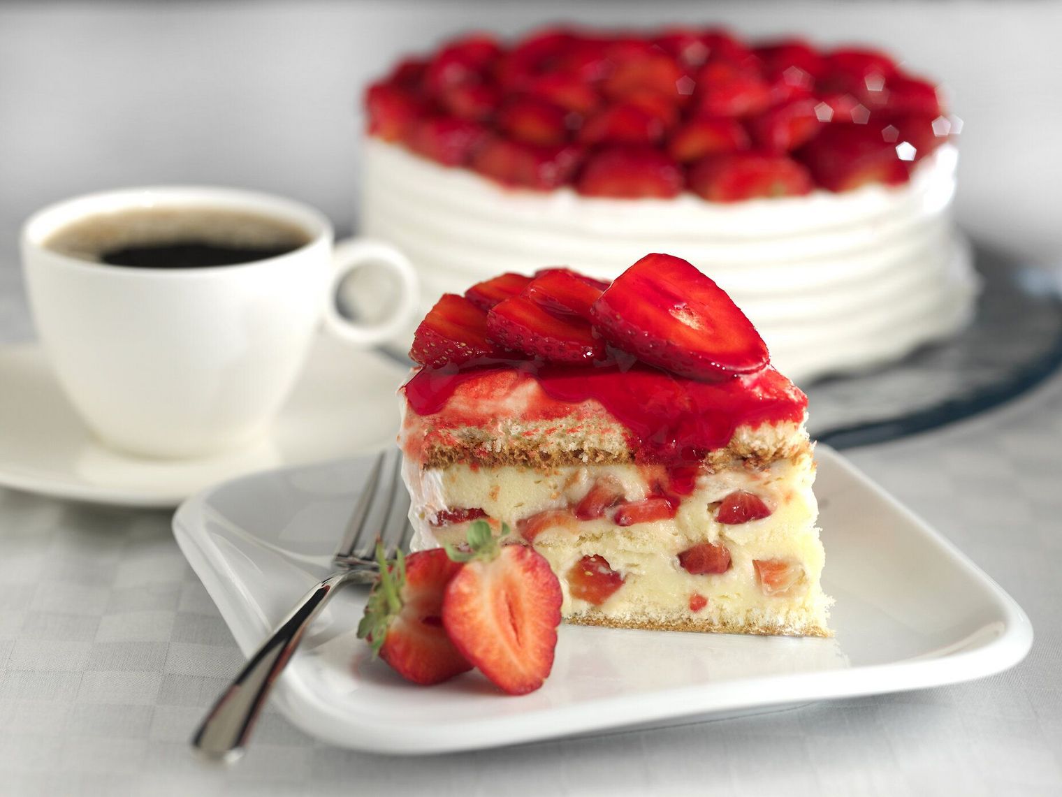 Stück Erdbeertorte mit Kaffee im Hintergrund