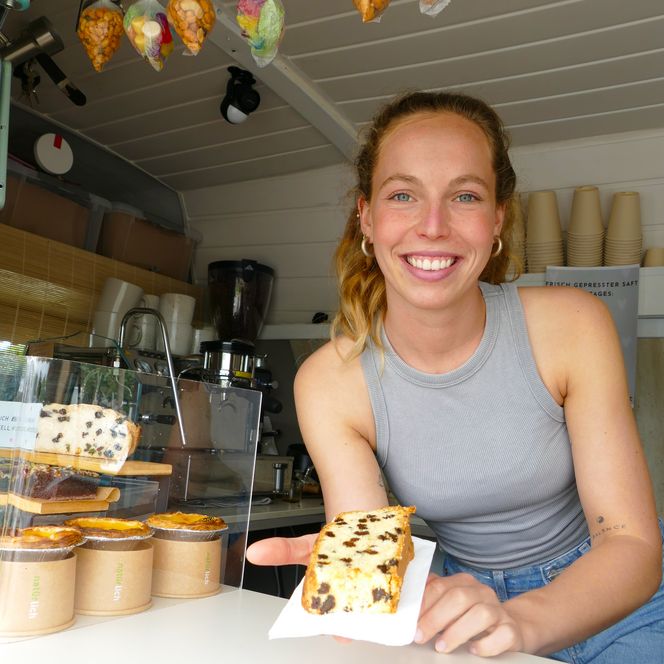 Lächelnde Frau reicht Kuchen über Theke im Verkaufswagen