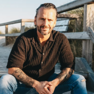 Sepp Reisenberger sitzt am Strandzugang auf Sylt