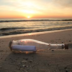 Flaschenpost am Strand bei Sonnenuntergang.