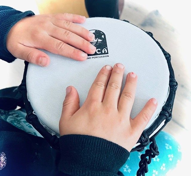 Zwei Kinderhände liegen auf einer kleinen Trommel.
