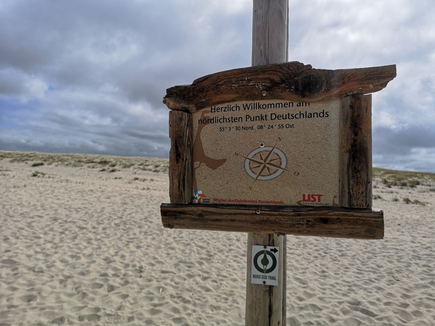 Holzschild am Strand mit Koordinaten des nördlichsten Punkts Deutschlands.
