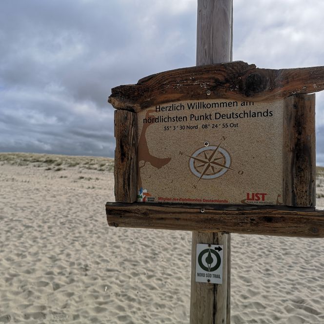 Holzschild am Strand mit Koordinaten des nördlichsten Punkts Deutschlands.
