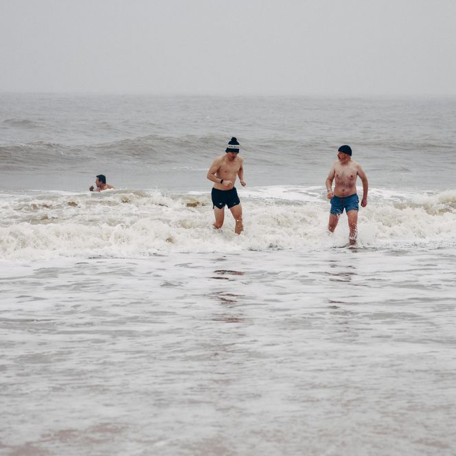Drei Männer baden im Winter in der Nordsee bei Westerland.