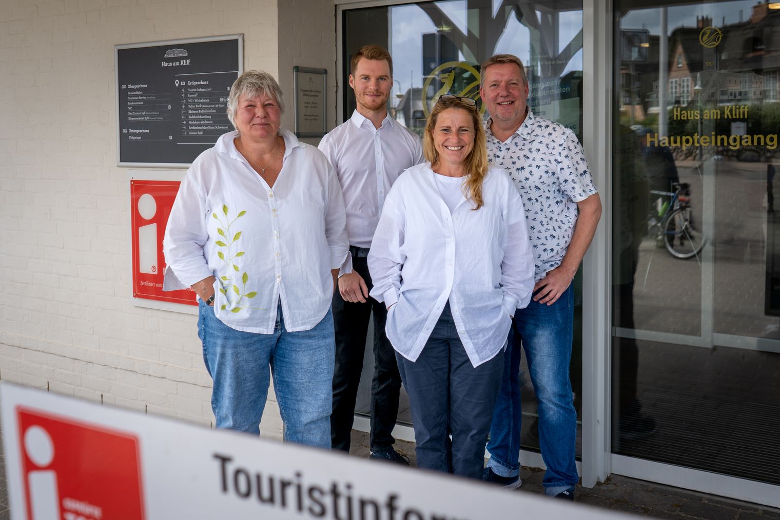 vier Mitarbeitende der Tourist-Information stehen vor dem Haus am Kliff und lächeln in die Kamera