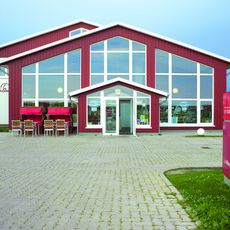 Sylter Schokoladenmanufaktur in Tinnum Aussenansicht Außenansicht der Sylter Schokoladenmanufaktur mit roter Fassade und Sitzplätzen.