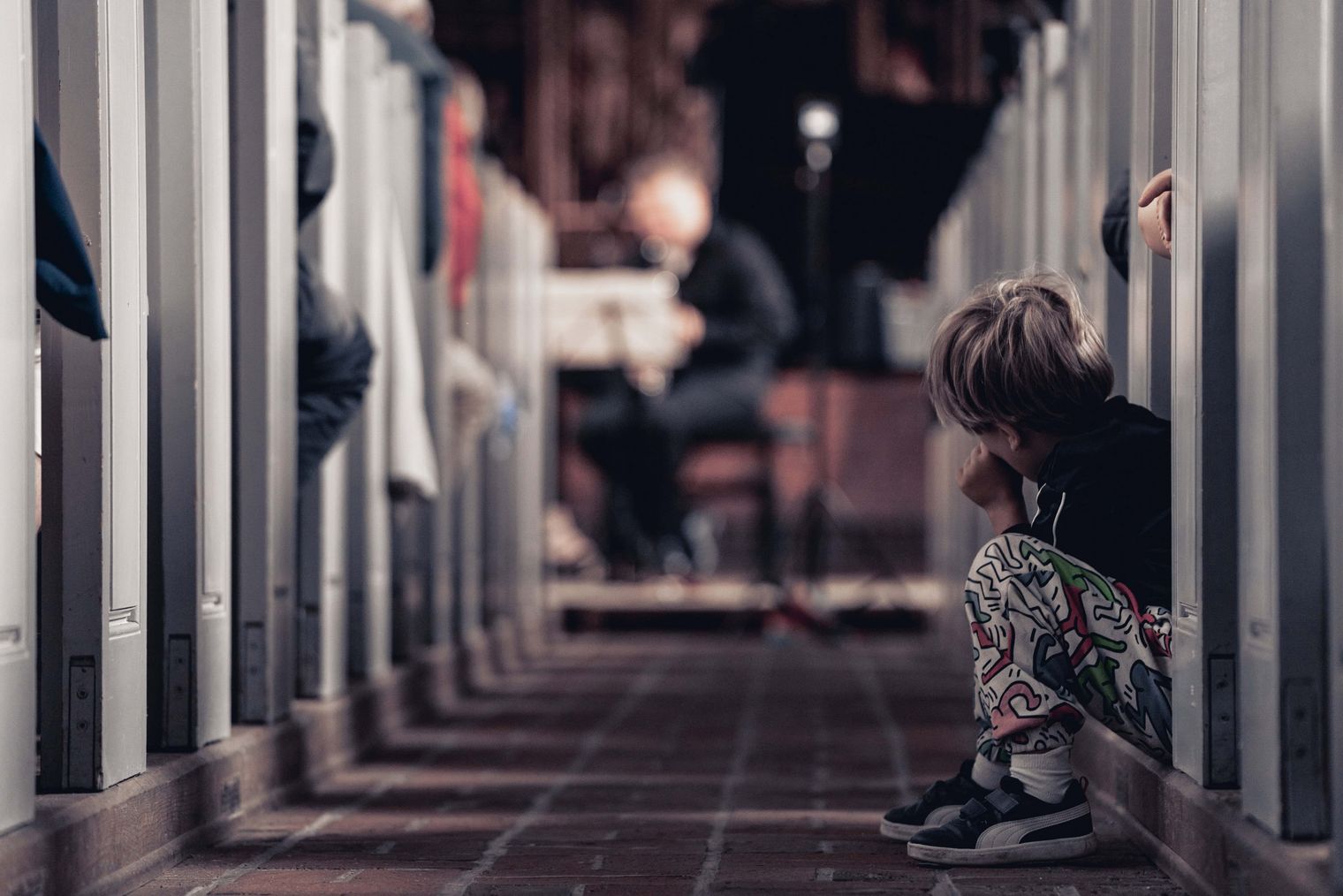 Kind sitzt auf Boden und hört aufmerksam einem Konzert zu.