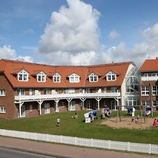Backsteingebäude mit Spielplatz und Strandkörben auf Rasenfläche.