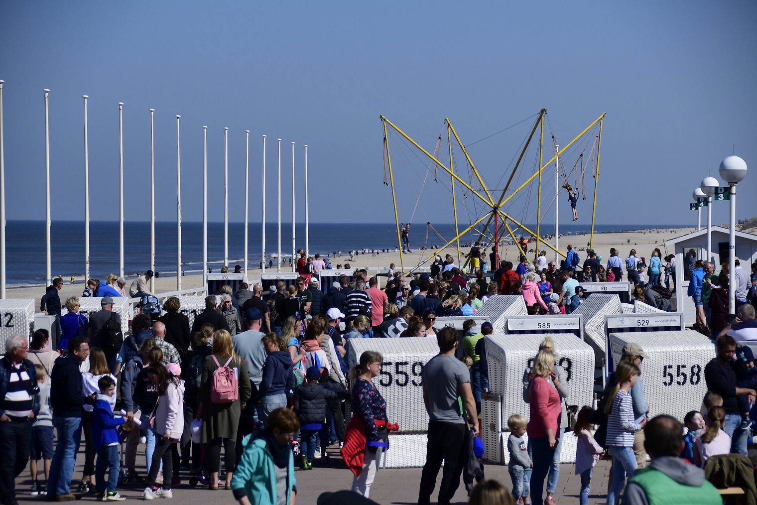 Menschen tümmeln sich auf der Westerländer Promenade mit Trampolin im Hintergrund