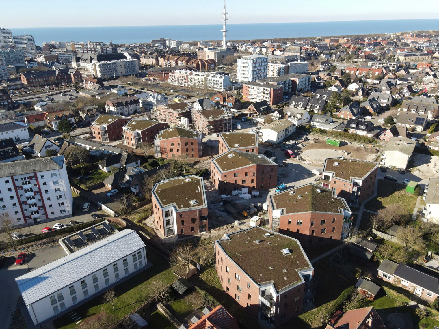 Luftbild moderner Wohnhäuser im Quartier Westhedig, dahinter Westerland und die Nordsee.