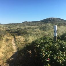 Reitweg durch Dünen mit Hufeisen-Markierung, Uwe-Düne und Leuchtturm im Hintergrund.