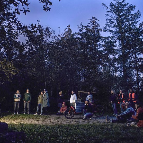Menschen schauen in einem Wald bei Dämmerung einen Film.