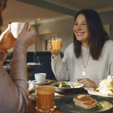 Frühstücksfreude unter Freundinnen im Februar auf Sylt: Ein Lächeln und ein Glas Saft Zwei Frauen frühstücken und stoßen mit Saft und Kaffee an