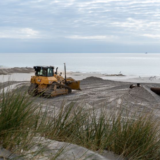 Bagger verteilt den angespülten Sand am Strand