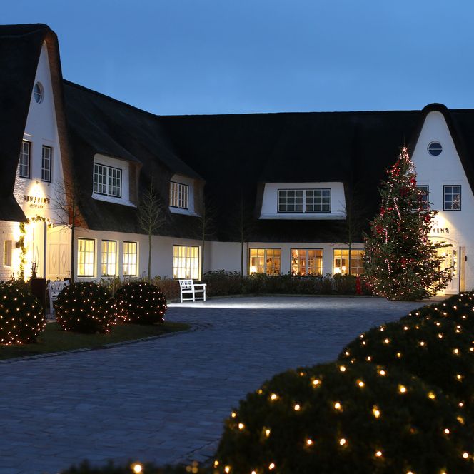 Außenaufnahme des Severin's Resort & Spa zur Weihnachtszeit mit festlicher Beleuchtung und einem großen, geschmückten Weihnachtsbaum im Hof. 
