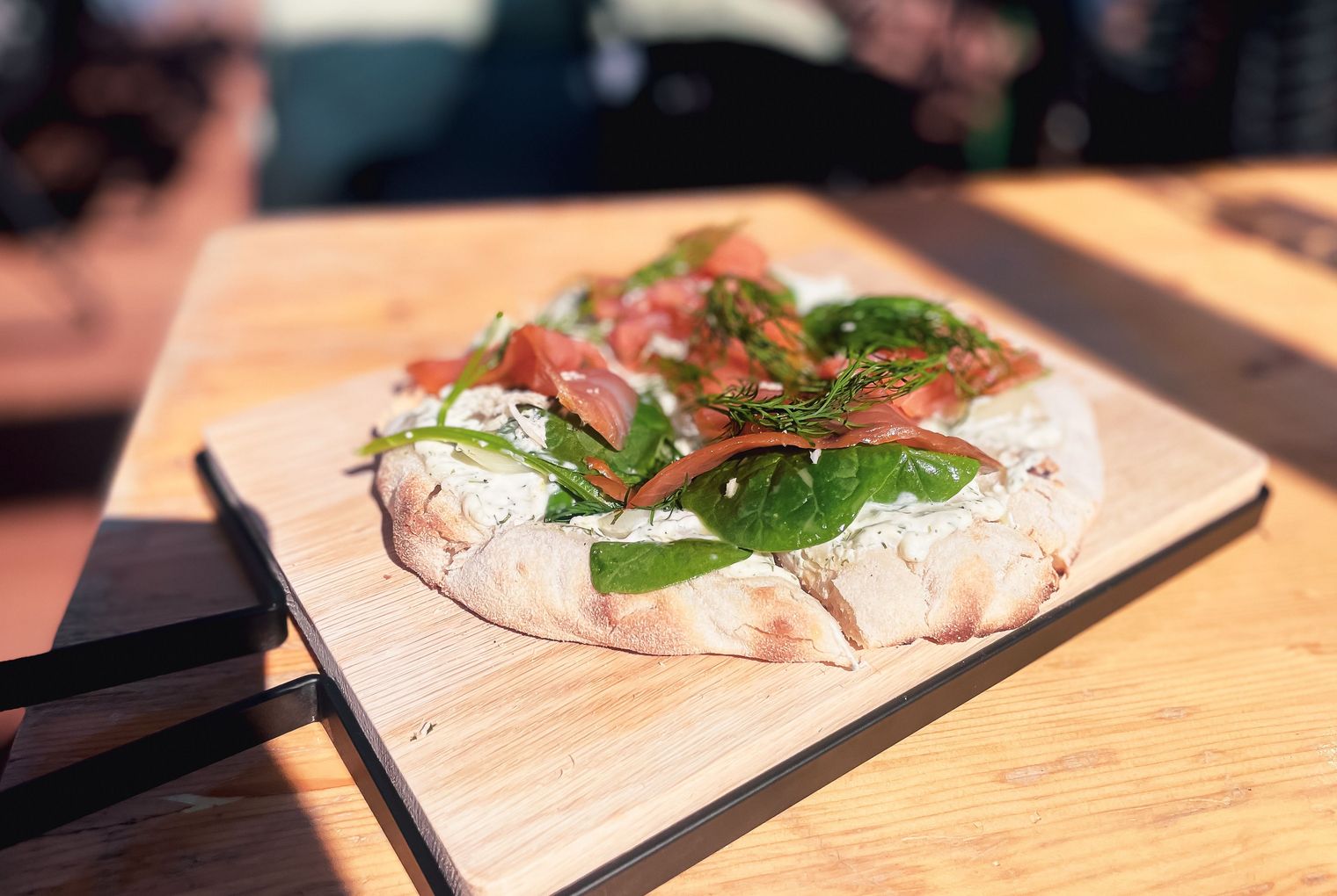 Fladenbrot mit Lachs, Spinat und Kräutercreme auf Holzbrett