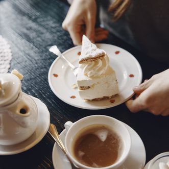 Sahnige Tortenauszeit mit Tee auf Sylt Teller mit Sahnetorte und Tasse Tee auf Holztisch