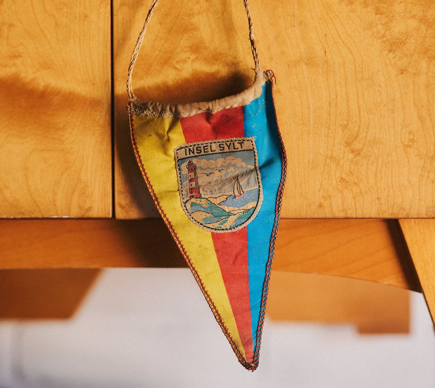 Bunter Wimpel mit der Aufschrift "Insel Sylt" und Leuchtturm-Motiv.