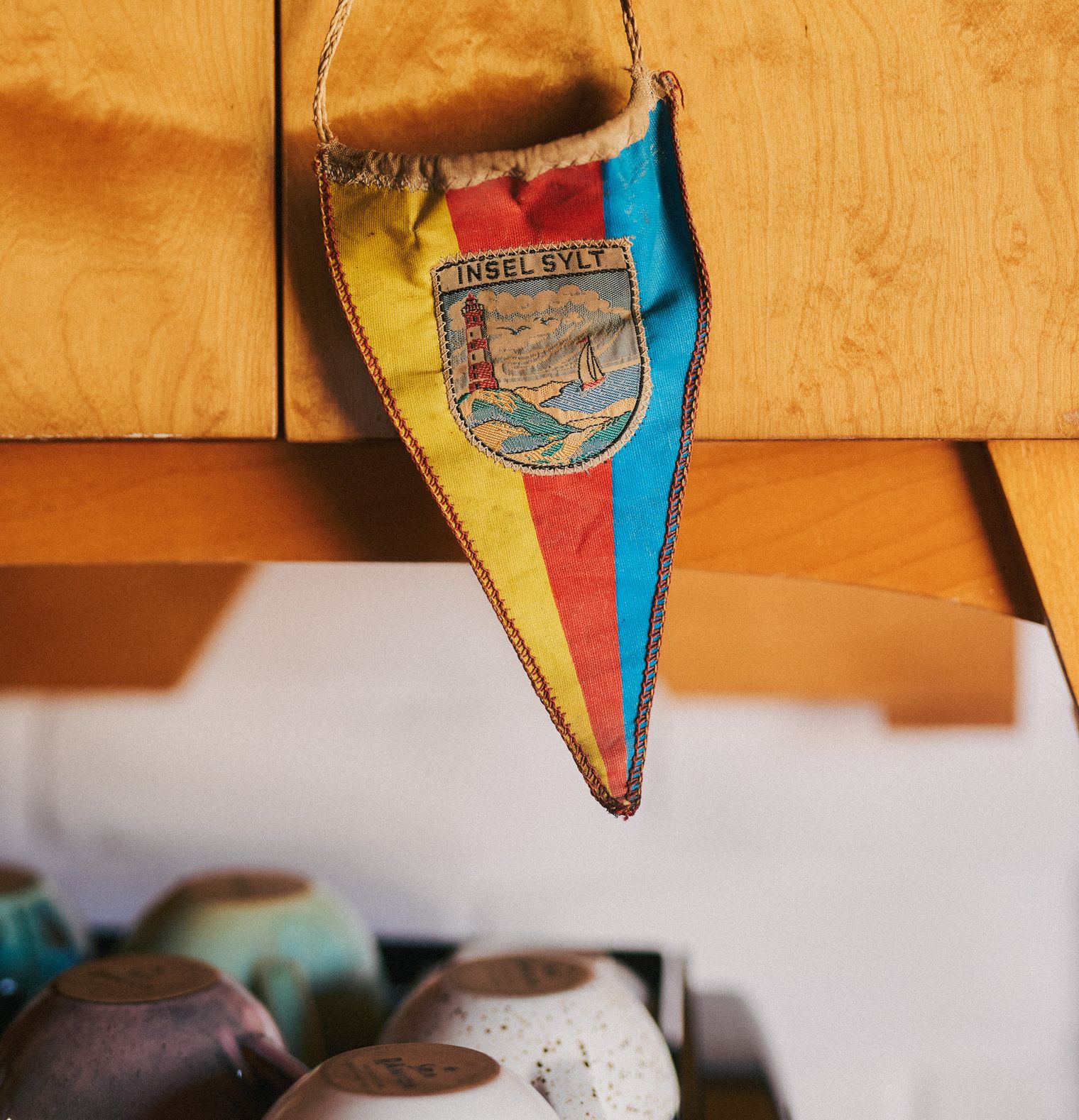 Bunter Wimpel mit der Aufschrift "Insel Sylt" und Leuchtturm-Motiv.